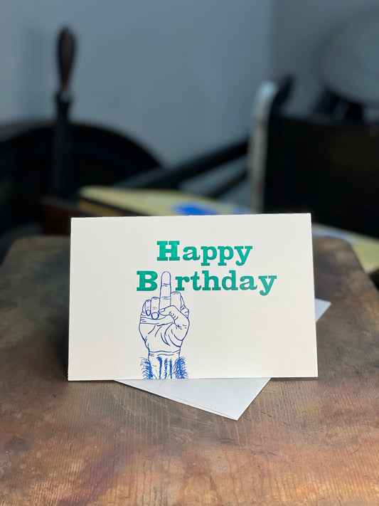 Happy Birthday with Middle finger 4x6in letterpress greeting card with The Rugged Press in background